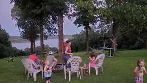 A group of people sitting on plastic chairs outdoors with a lake in the background. - Spacious Norfork Lake View Bunkhouse, Resort Amenities, Family/Fishermen/Pets (Gamaliel)
