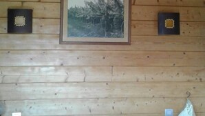 A wooden cabin room with a bed, a hanging light fixture, and two framed pictures on the wall. - 90m² chalet overlooking Lake Annecy (Saint-Jorioz)
