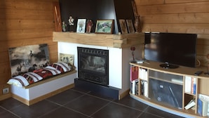 A living room with a fireplace, a television, and a bookshelf. - 90m² chalet overlooking Lake Annecy (Saint-Jorioz)