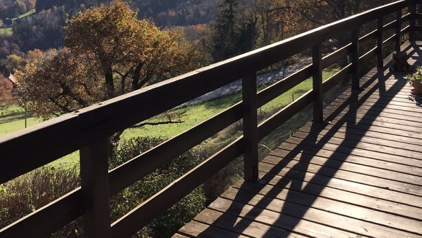 A wooden deck with a railing overlooking a valley with autumn-colored trees and distant mountains. - 90m² chalet overlooking Lake Annecy (Saint-Jorioz)