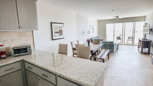 Une cuisine moderne dotée de plans de travail en granit, d’un four encastré et d’un coin repas avec une banquette et des chaises.