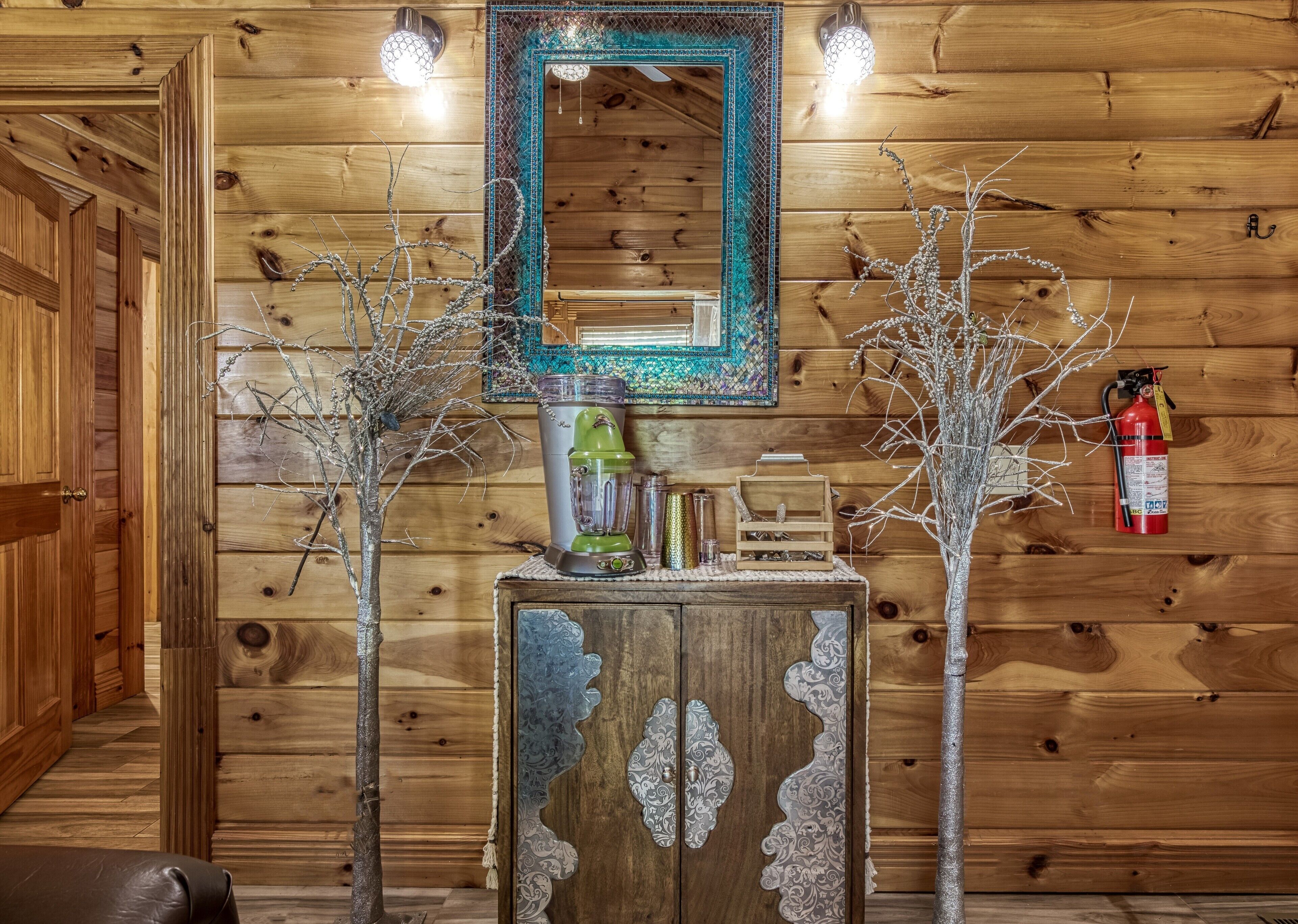 Interior de madera con un espejo, ramas decorativas, una licuadora y un extintor.