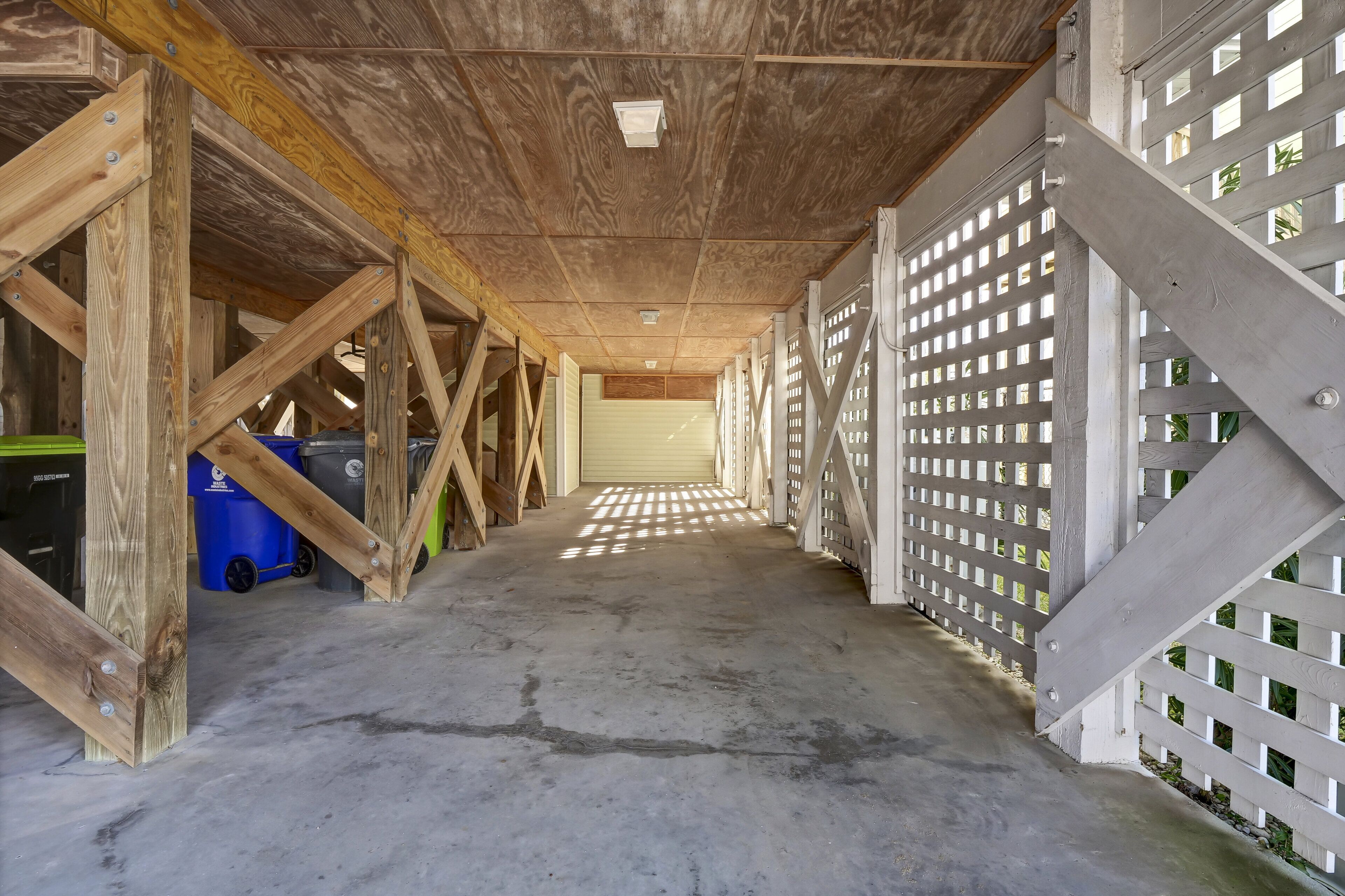 An unfinished interior with exposed wooden beams, a concrete floor, and a white lattice partition.