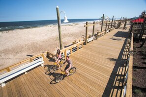 A wooden boardwalk with a sandy beach and ocean in the background.