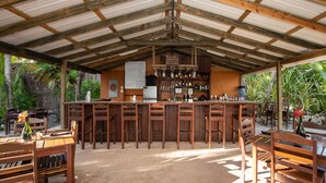 Ett rustikt utomhusområde med bar, möbler i trä och ett tak av metall.