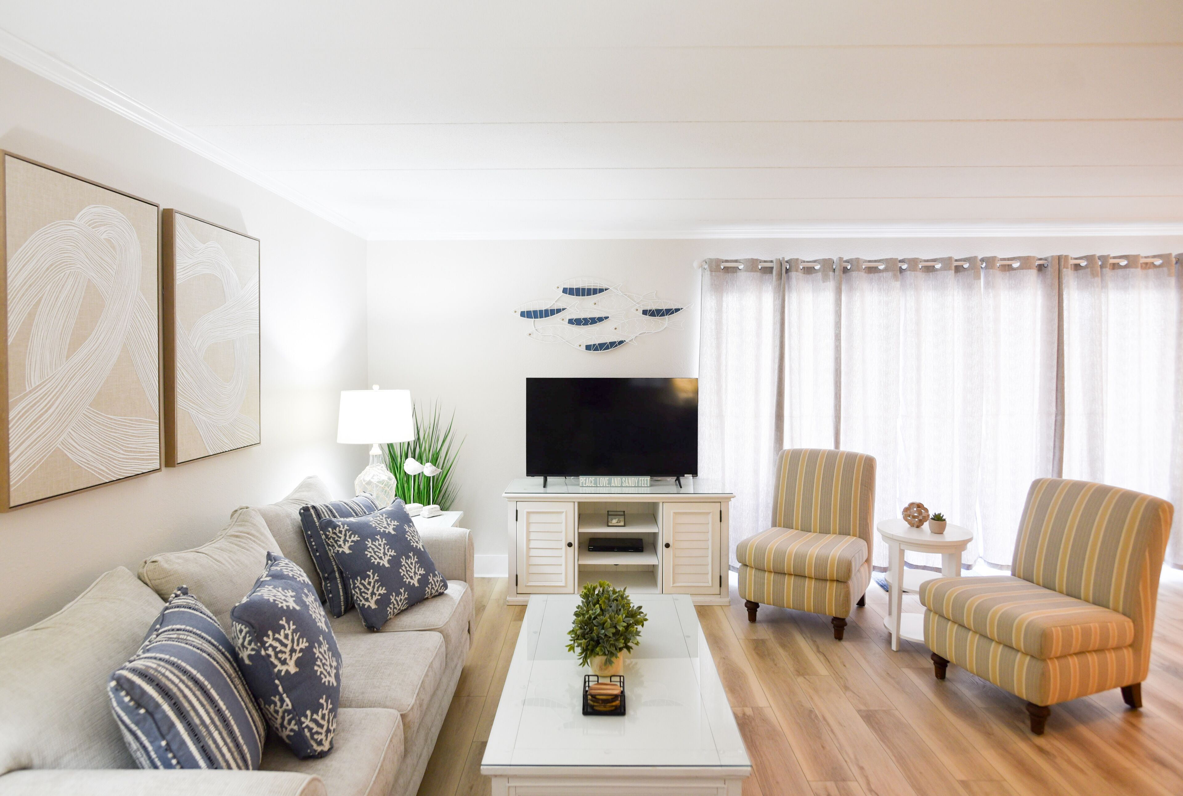 A living room with a sofa, armchairs, a coffee table, a TV, and decorative items.