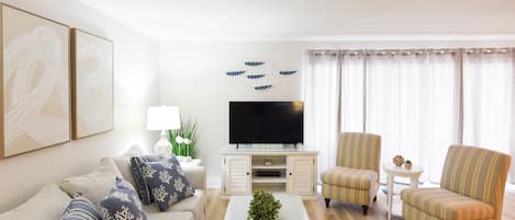 A living room with a sofa, armchairs, a coffee table, a TV, and decorative items.