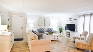A modern living room with a sofa, armchairs, a coffee table, and a TV. - Direct Ocean Front Building, Oceanview, Mid-Town 39th St, First Floor Unit  (Ocean City)