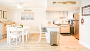 A modern kitchen with white cabinetry, a central island, and a stainless steel refrigerator. - Direct Ocean Front Building, Oceanview, Mid-Town 39th St, First Floor Unit  (Ocean City)