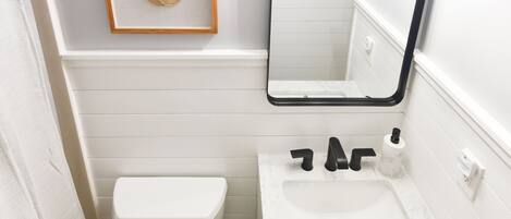 Une salle de bain avec des toilettes, un lavabo et un miroir.