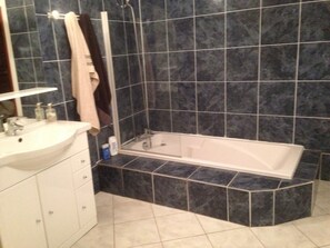 Een badkamer met een wastafel, spiegel en bad.