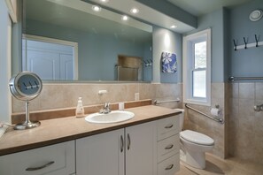 Een badkamer met wastafel, spiegel, toilet en douche.