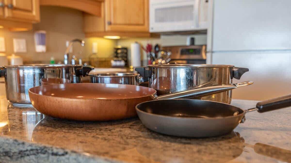 A kitchen counter with various cookware including pots, pans, and a frying pan.