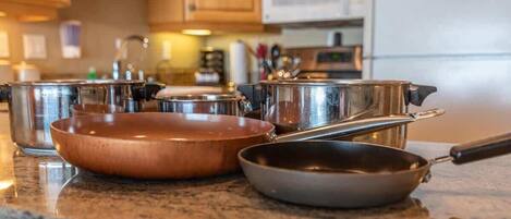 A kitchen counter with various cookware including pots, pans, and a frying pan.
