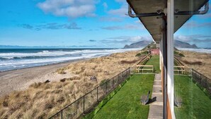 Une vue sur la côte, avec une zone herbeuse, une clôture en bois et un bâtiment visible au loin.