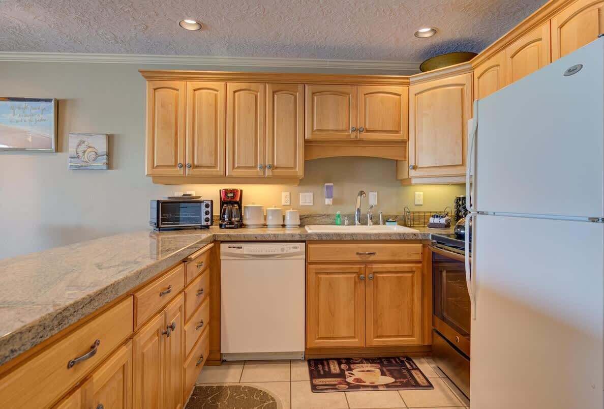 A kitchen with wooden cabinets, a dishwasher, a refrigerator, and a coffee maker.