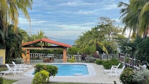 Un área de piscina con terraza techada, sillas de descanso y césped bien cuidado.