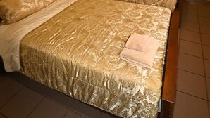 Habitación de hotel con dos camas, cada una con una colcha y almohadas estampadas. Entre las camas, una mesita de noche con lámpara.