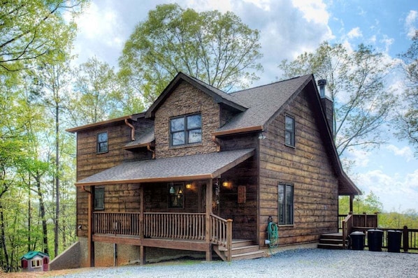 A rustic log cabin with a porch, a chimney, and a small deck area.