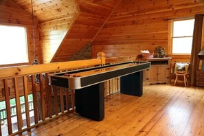 A wooden interior with a pool table, a window with curtains, and a stone wall. - Sarah's Mountain Hideaway by Mountain Oasis | Cozy Cabin in Coosawattee River Resort (Ellijay)