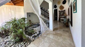Un espacio al aire libre cubierto con un sendero de piedra, un pequeño jardín con helechos y una escalera que conduce a un nivel superior.