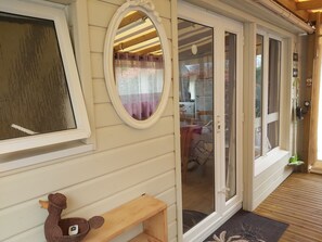 Un banco de madera con un adorno, una ventana con cortina y un ventanal corredizo que da a un espacio interior.