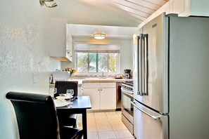 A compact kitchen with a refrigerator, stove, and dining area.
