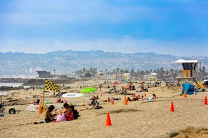 A beach with lifeguard towers, umbrellas, and people relaxing.
