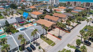An aerial view of a residential area with houses, palm trees, and a street.