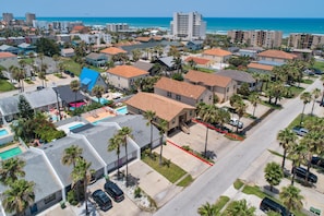 An aerial view of a residential area with houses, palm trees, and a street. - Multi-Family Beach Retreat • Private Heated Pool • 3 Min Walk to Beach (South Padre Island)