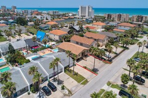 Residential neighborhood with single-family homes and apartment buildings, surrounded by palm trees and near the ocean.