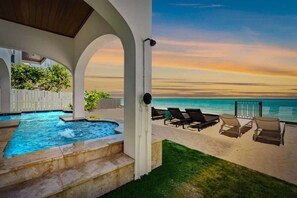 A pool with a view of the ocean, lounge chairs, and a white fence. - Serendipity Deux -Luxury Beachfront Pool & Spa - Golf Cart -Elevator (Anna Maria)