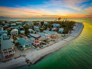 Une zone résidentielle côtière avec des maisons le long de la plage, un ciel dégagé et un coucher de soleil.
