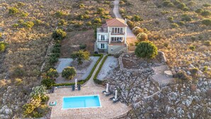 Una casa con piscina, rodeada de un jardín y un sendero de piedra.