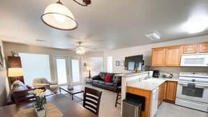 A modern kitchen with a dining area, wooden cabinets, a microwave, and an oven. - Country Cousins | Pet-Friendly | 1st Floor | Pool (New Braunfels)