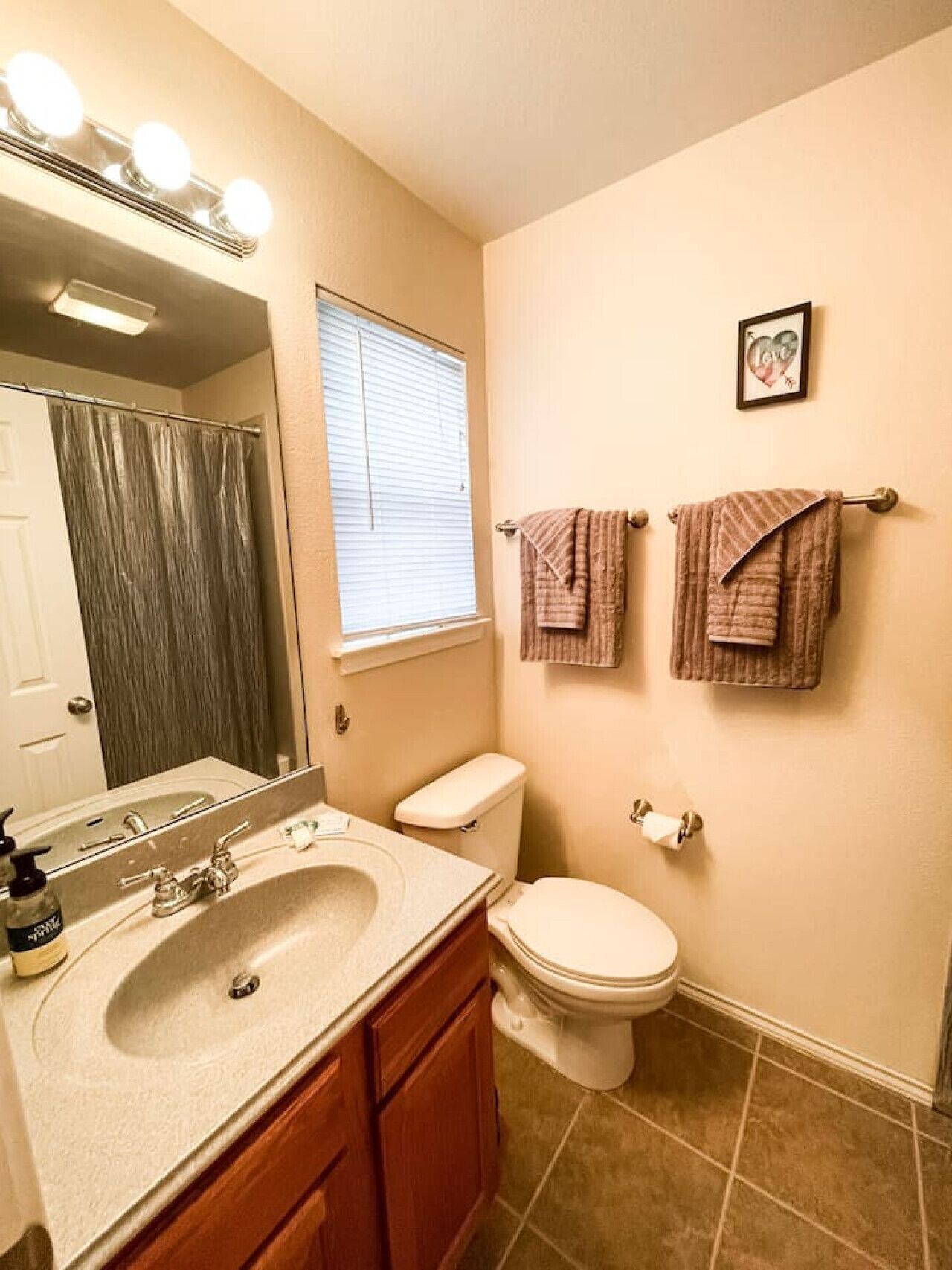 A bathroom with a sink, mirror, toilet, and two towels on a rack.