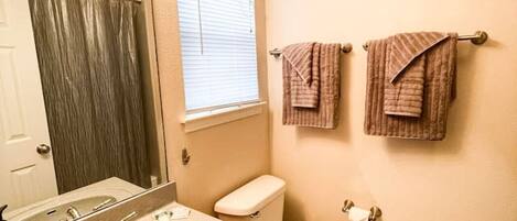A bathroom with a sink, mirror, toilet, and two towels on a rack.
