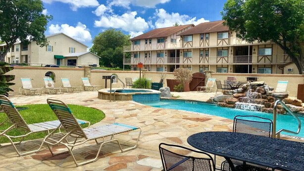 A hotel with a swimming pool, lounge chairs, and a patio area. - Country Cousins | Pet-Friendly | 1st Floor | Pool (New Braunfels)