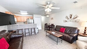 A living room with a brown leather sofa, a coffee table, and a dining area with a table and chairs. - Country Cousins | Pet-Friendly | 1st Floor | Pool (New Braunfels)
