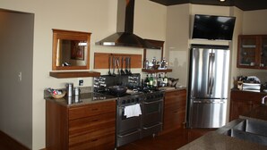 Una cocina moderna con electrodomésticos de acero inoxidable, armarios de madera y un televisor de pantalla plana sobre la estufa.