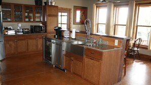 Cocina con armarios de madera, electrodomésticos de acero inoxidable y encimera de granito.