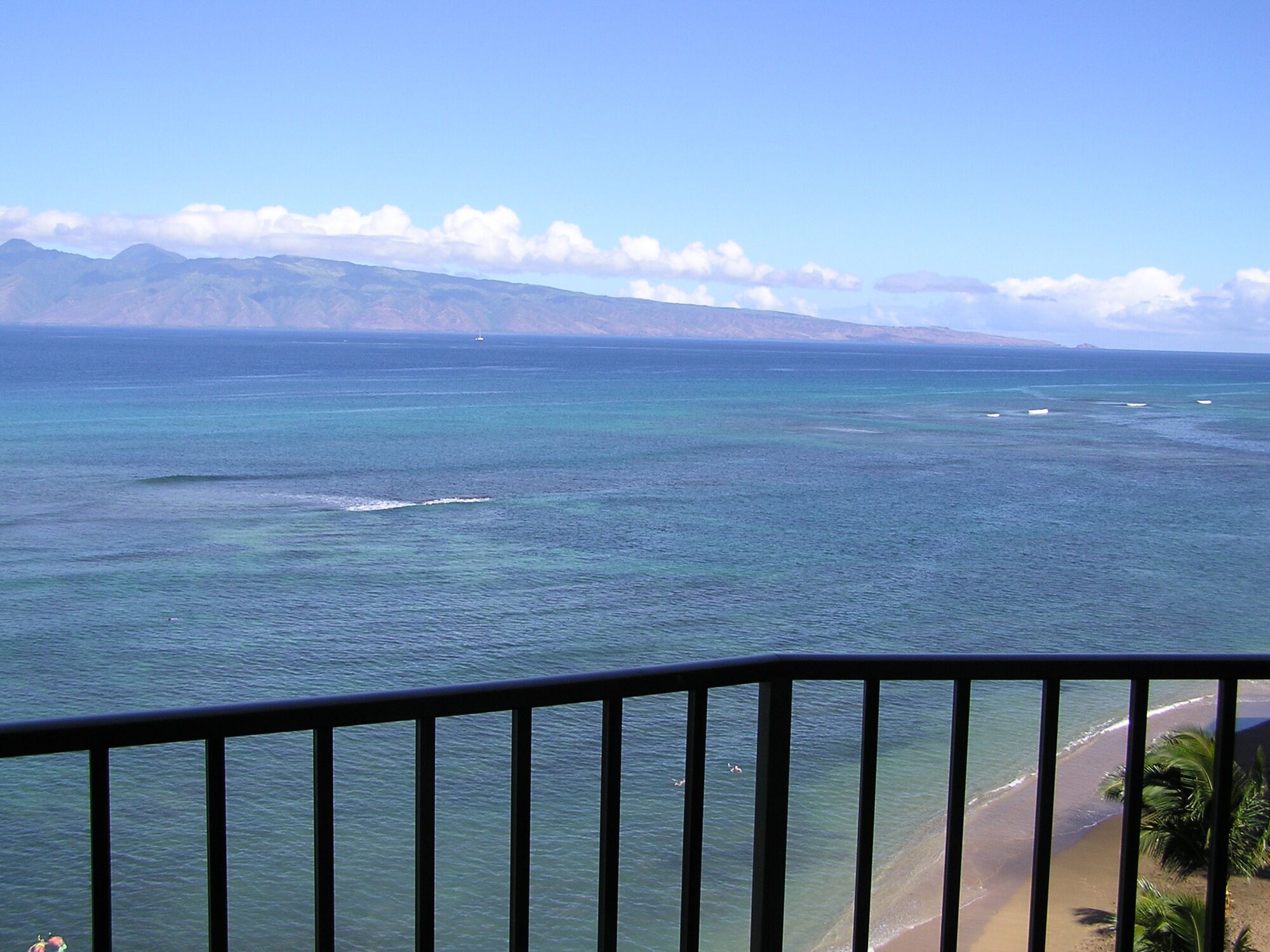 Une vue sur la côte, avec un ciel dégagé, une plage et des montagnes à l’horizon.