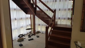 Uma escada de madeira leva a uma varanda com cortinas leves.