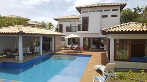Uma villa moderna com piscina, área de estar ao ar livre e um alpendre coberto.