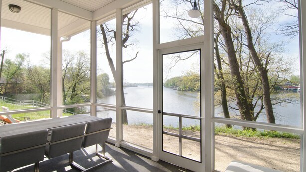 Un espacio de estar techado al aire libre con vistas a un río y árboles.