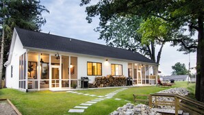 Una casa moderna con un porche cubierto, un sendero de piedra y una terraza de madera.