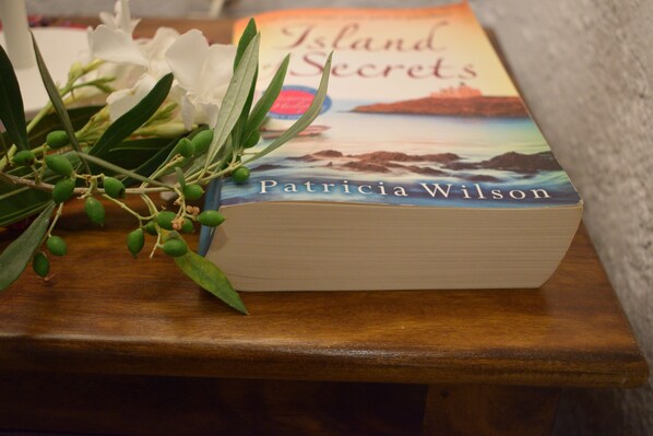 Un libro titulado 'Island Secrets' de Patricia Wilson sobre una superficie de madera.