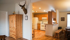 Una cocina con armarios de madera, cabeza de venado montada y una zona de comedor con banco.