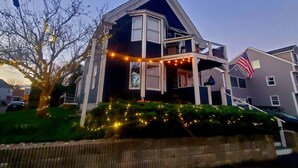 A two-story house with a balcony, a visible nameplate, and an American flag. - City Amenities, Casco Bay Sunrises and Natural Beauty (Portland)