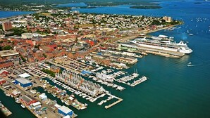 An aerial view of a coastal city with a marina, including boats and a cruise ship docked. - City Amenities, Casco Bay Sunrises and Natural Beauty (Portland)